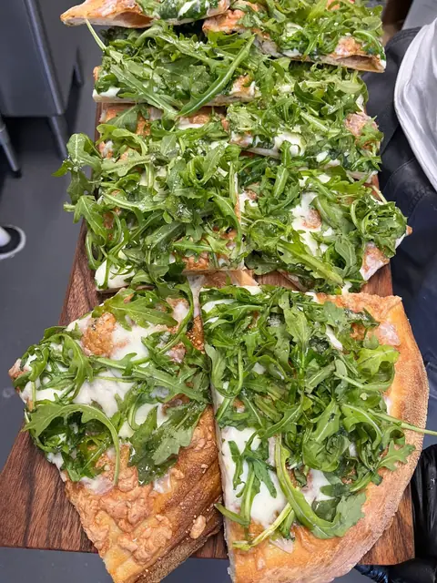 Pizza topped with fresh rocket on a board
