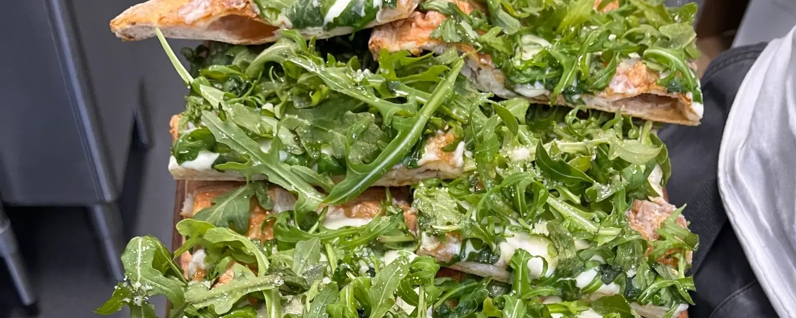 Sliced pizza piled with fresh rocket