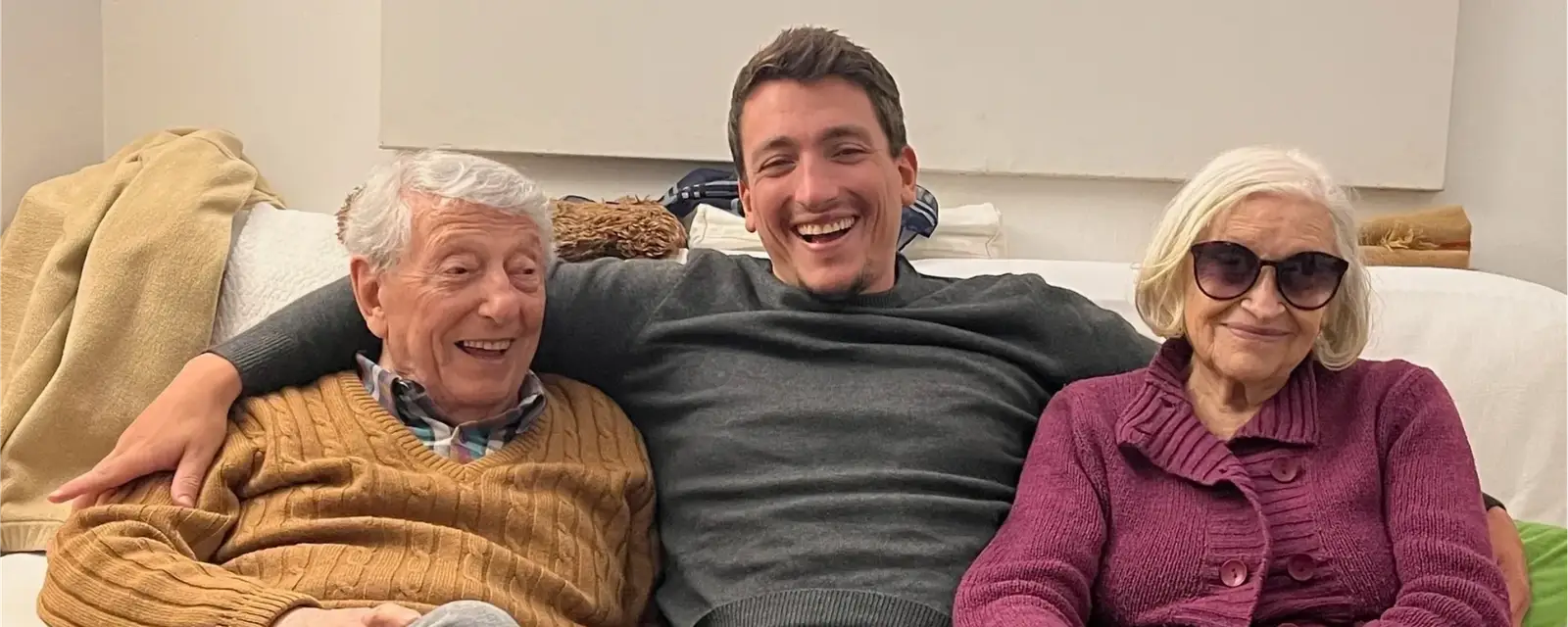 Giorgio sitting on a couch between his grandparents, all three smiling